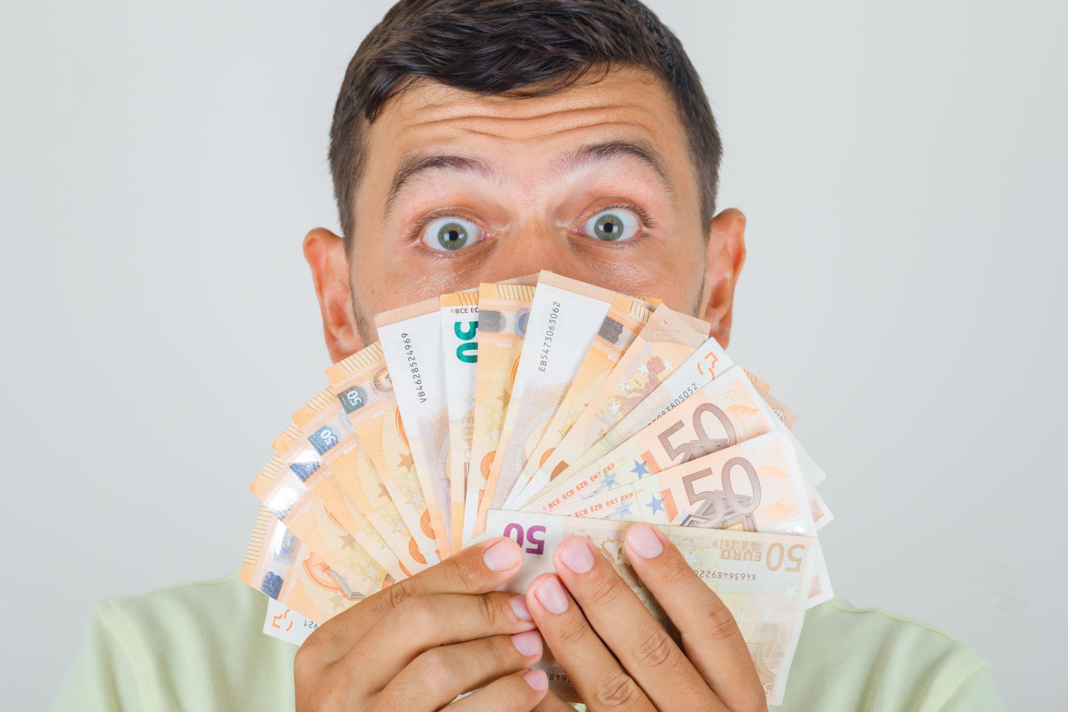 Brasileiros que trabalham em Portugal: como converter euros em reais? man holding euro banknotes t shirt looking shocked1